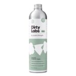 Tall silver and green bottle labeled "Dirty Labs Bio Laundry Detergent Refill" with notes of magnolia, bergamot, and cedar. Contains 640 mL.